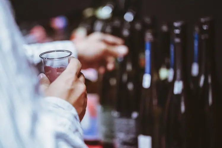 差し出されたグラスと並ぶ日本酒の瓶