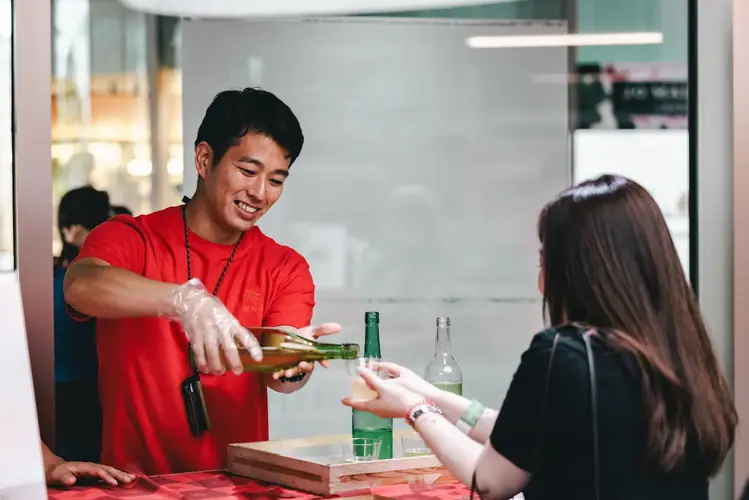 来場者のカップに酒を注ぐスタッフ